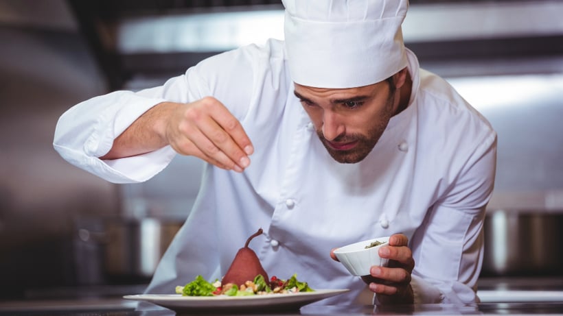 Chef sprinkling spices on dish